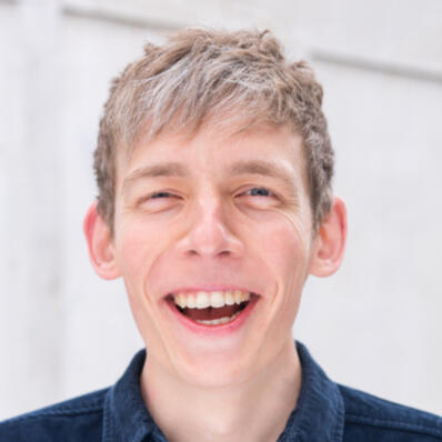 image of spencer rust (a white man in a blue shirt) smiling