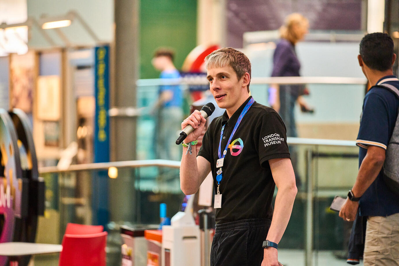 image of spencer rust (a white man in a polo shirt) holding a microphone at the London Transport Museum